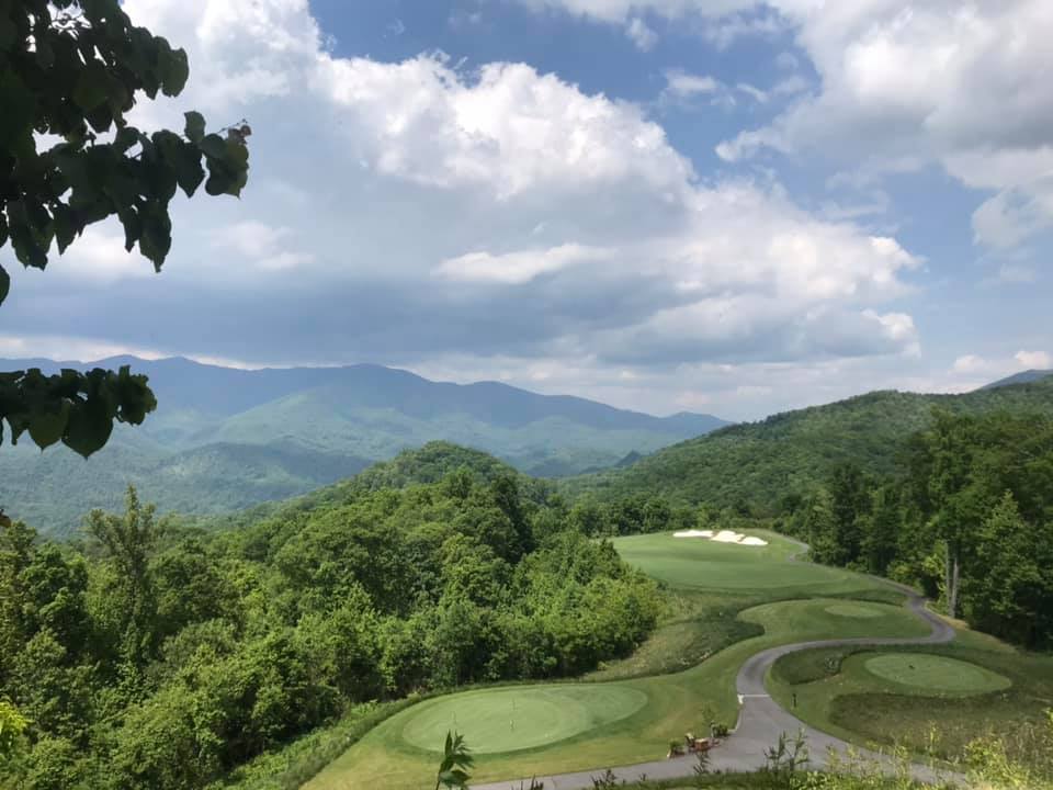 Golf course green with mountain range in distance